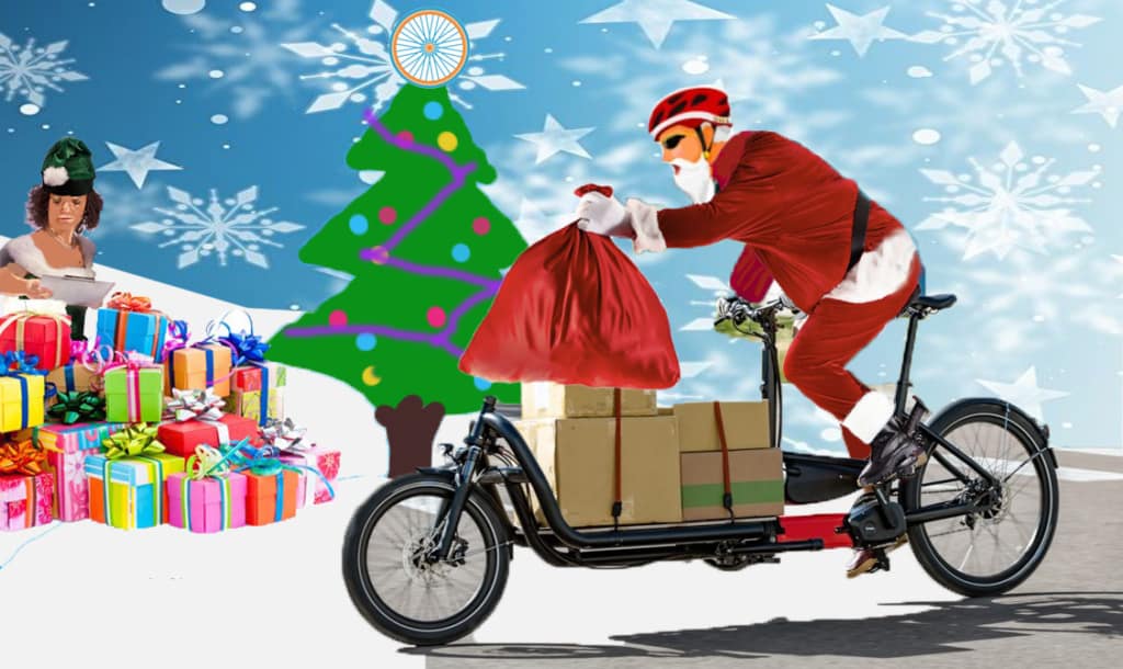 Santa cycling on a cargocycle holding his sack with the cargocycle full of boxes. In the background a health and safety elf checks their clipboard from behind a pile of presents. The background is cartoony with over sized snowflakes and a christmas tree, the tree has the Wheels for Wellbeing orange and blue wheels logo at it's pinnacle.