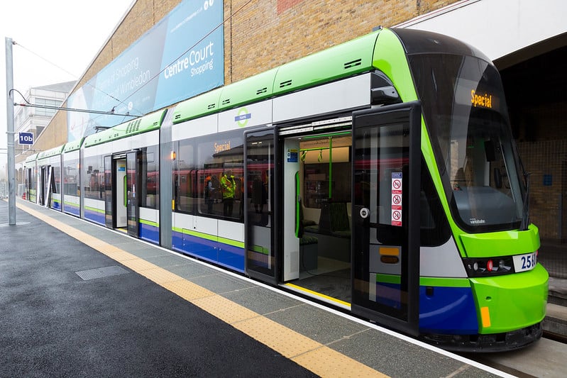 A tram at the station. The doors are open and the floor of the tram is flush with the platform. The edge of the platform is clearly marked with colour and tactile paving.