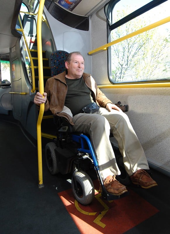 A man in a wheelchair in the wheelchair space on a bus.