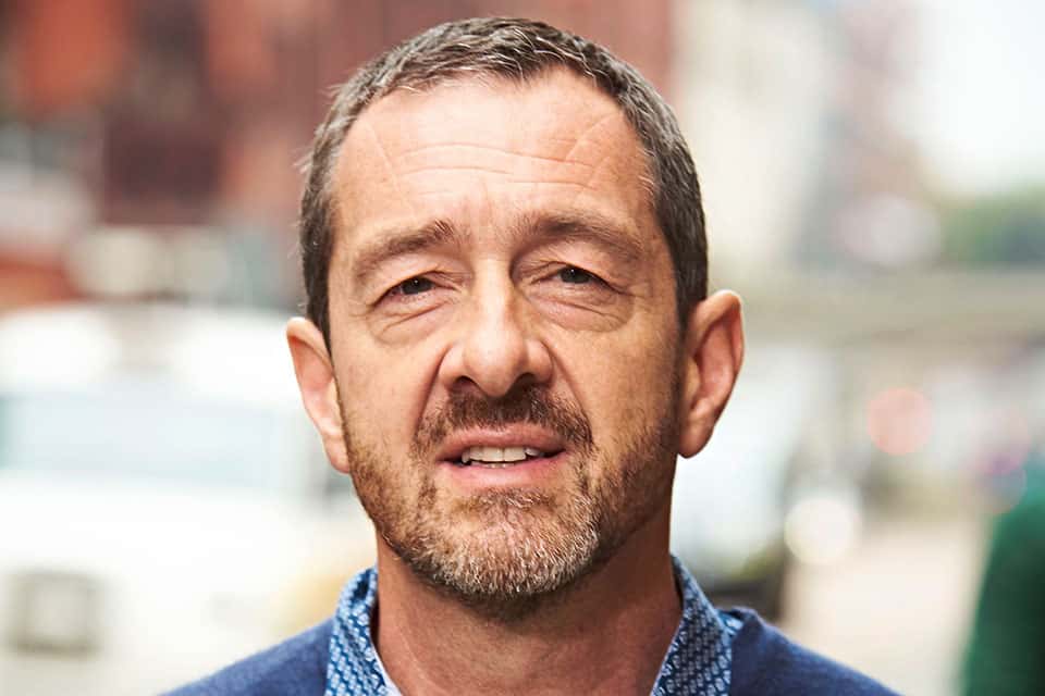 An image of Chris Boardman the new interim commissioner at Active Travel England, it shows his face and shoulders only, the background is blurry, and he has a blue shirt just visible one. 