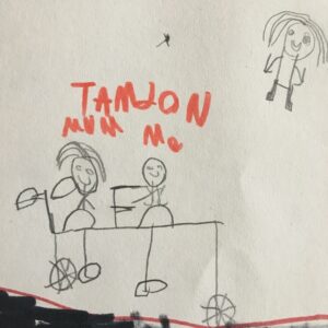 A pencil drawing of a tandem ctclewith two people riding it. Another person is floating in the sky. The words "tamdon Mum Me" are written in orange felt tip labelling the tandem.