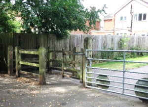 Photo shows a traffic-free path access with a wide metal farm style gate to the right and a complex wooden kissing gate to the left.