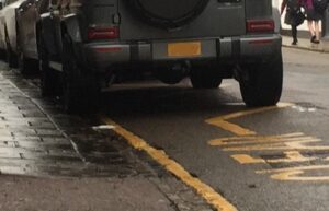 Car parked on ‘school keep clear’ zig-zag, with two wheels on the kerb. 