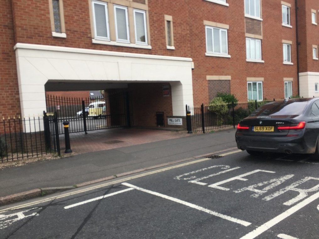 A large apartment block with dropped kerb entrance into a gated car park