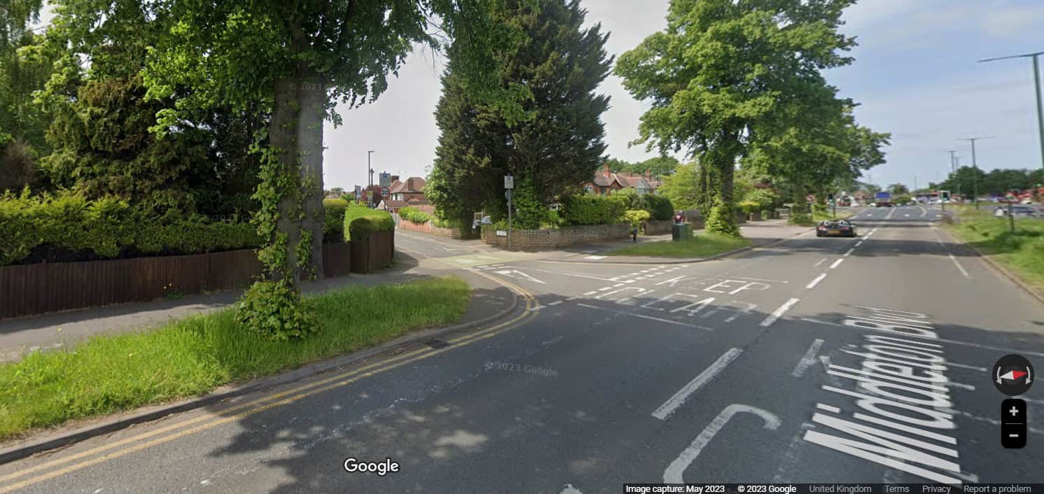 Screenshot of Google Streetview showing 40mph dual carriageway turning onto 20mph narrow side street. The main road has wide verges between the carriageway and the footway/cycleway The side street has a green strip across the carriageway between buff blister tactiles. White paint markings instruct vehicles to give way to pedestrians and cycles crossing. The vehicle carriageways on the side road are very narrow - drivers will have to slow to very low speeds or give way to pass each other.