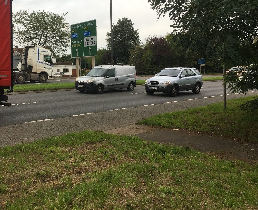 A busy dual carriageway with a small uncontrolled crossing footway across it. The crossing point has buff tactile paving and a flush dropped kerb