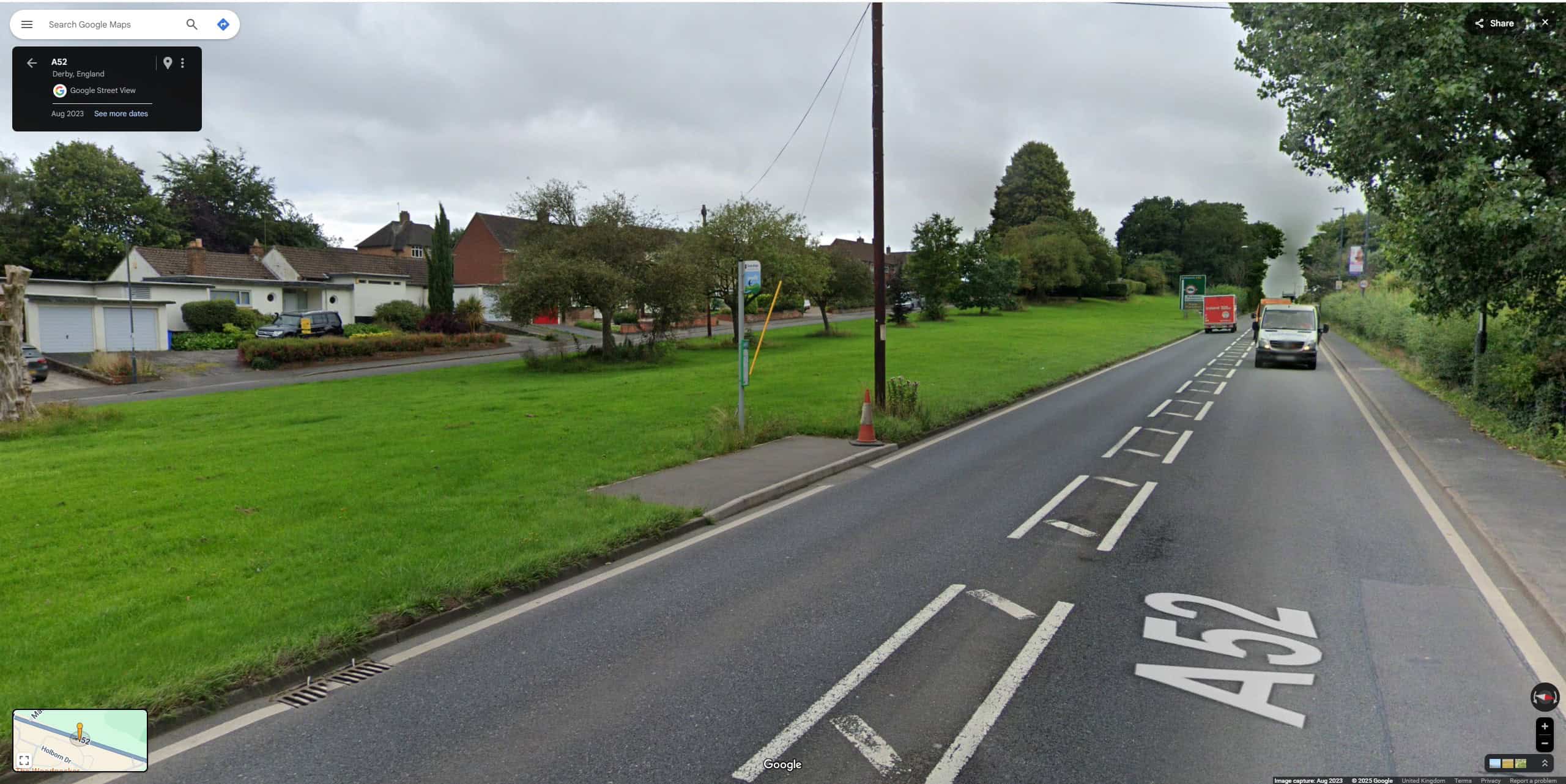 A suburban bus stop on the A52 in Mackworth, Derby which is just a rectangle of asphalt set into a large grass area next to what is clearly a fast, busy road. There is a narrow footway on the opposite side of the road, and a suburban house-lined road visible beyond the grass area, but no accessible way for Disabled people to get to either. The bus stop, ironically enough, has a new raised kerb to make it accessible from a bus for people who need to use a ramp.